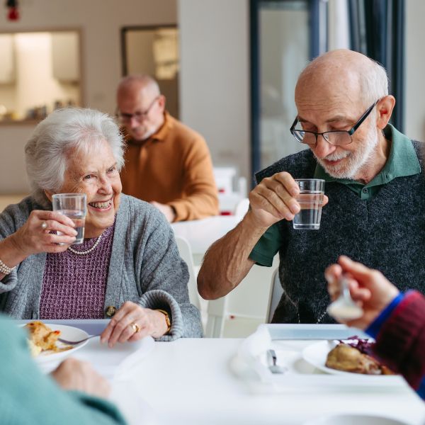 April Newsletter Age-Friendly Manitoba Close up image focused on two seniors at a community event, sitting at a table enjoying a meal.